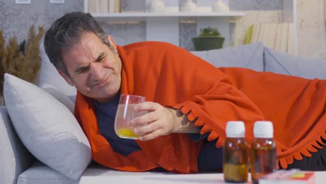 Hombre-Enfermo-Y-Exhausto-Descansando-En-Casa,-Bebiendo-Bebidas-Y-Medicamentos-Saludables,-Con-Ganas-De-Mejorar.